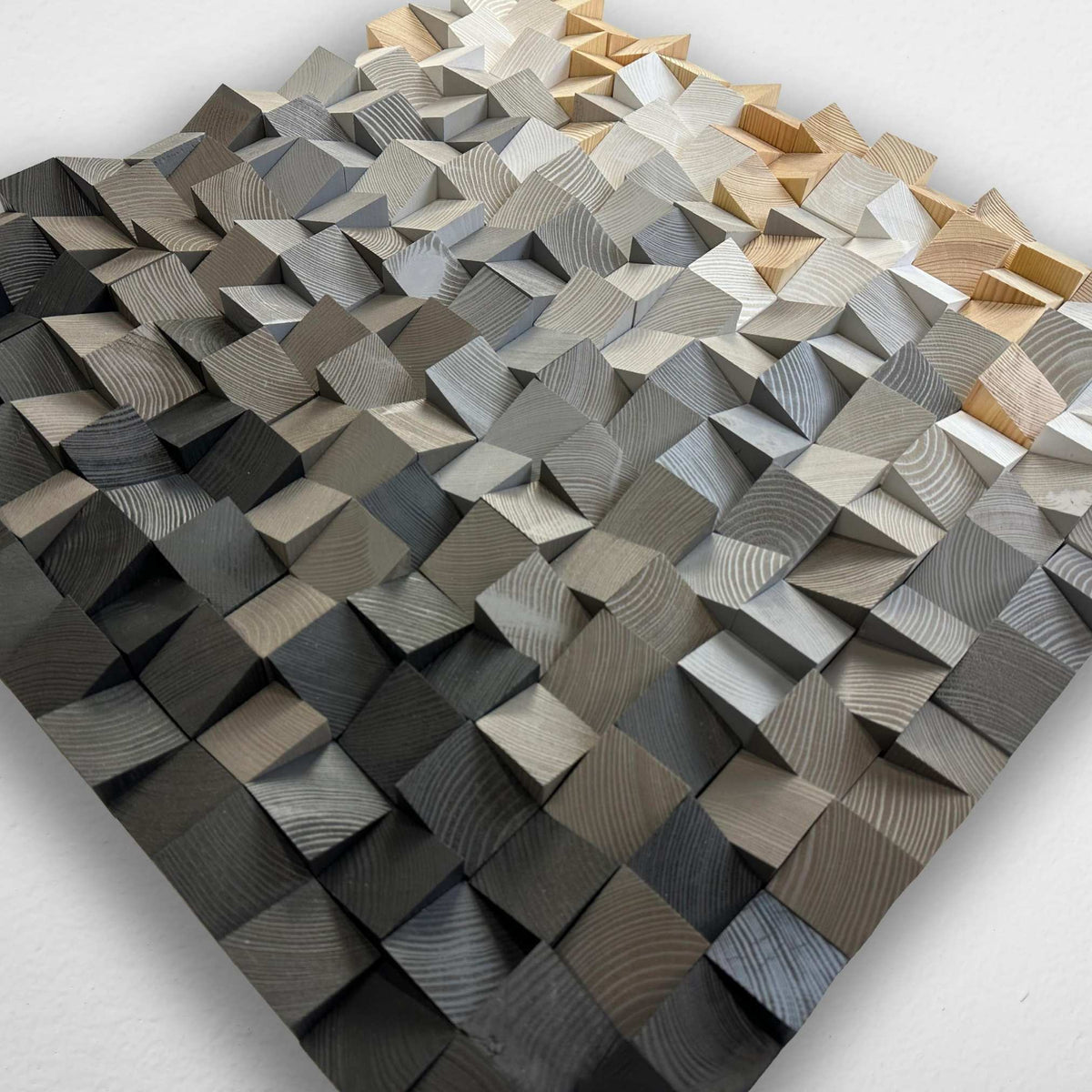 A square wooden geometric wall art piece featuring a 3D textured pattern of interlocking wedge blocks with visible wood grain, shown on a plain white background.