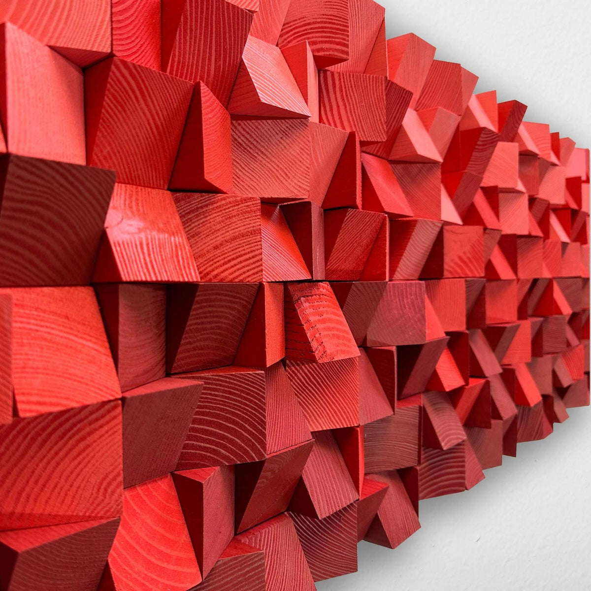 Red wooden geometric wall art featuring a 3D effect made of interlocking cube-like panels with visible wood grain, mounted on a light gray wall.