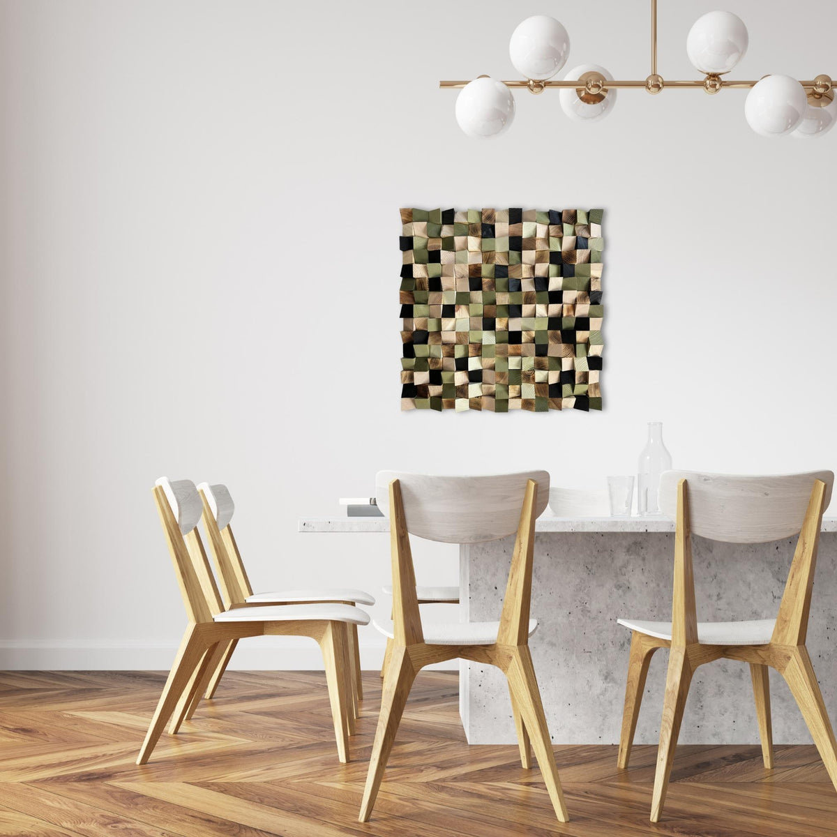 A square wall art piece with a patchwork mosaic of olive green, brown, beige, and black squares hangs on a white wall above a dining table and chairs in a modern room.